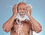 Water splash, skincare and black man isolated on blue background for face cleaning, beauty and using hands. Happy senior model or person with facial wash or hygiene for dermatology in studio action