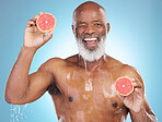 Black man, portrait smile and fruit for nutrition, vitamin C or skincare hydration against a blue studio background. Happy African American male smiling and holding grapefruit for health and wellness