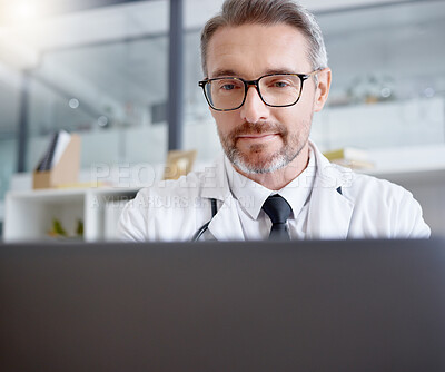 Buy stock photo Laptop, man and doctor working in hospital for healthcare, health and wellness in clinic. Computer research, medical professional or mature physician writing report, telehealth or online consultation