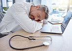 Man, doctor and laptop sleeping on desk from burnout, overworked or insomnia at the office. Tired male medical professional taking a nap, rest or asleep on table by computer at the workplace