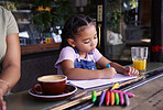 Girl child color in book at cafe, creative and drawing with crayons, family day to relax with learning and art in Atlanta. Young kid, growth and writing, education and creativity while at coffee shop