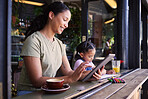 Black family, children and mother remote working at a cafe together with her daughter coloring in a book. Tablet, internet or coffee shop with a woman freelancer and her female child at a restaurant