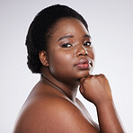 Confident black woman, hand and chin in skincare beauty, cosmetics or makeup against a gray studio background. Portrait of proud African American female plus size model in self love, care or facial
