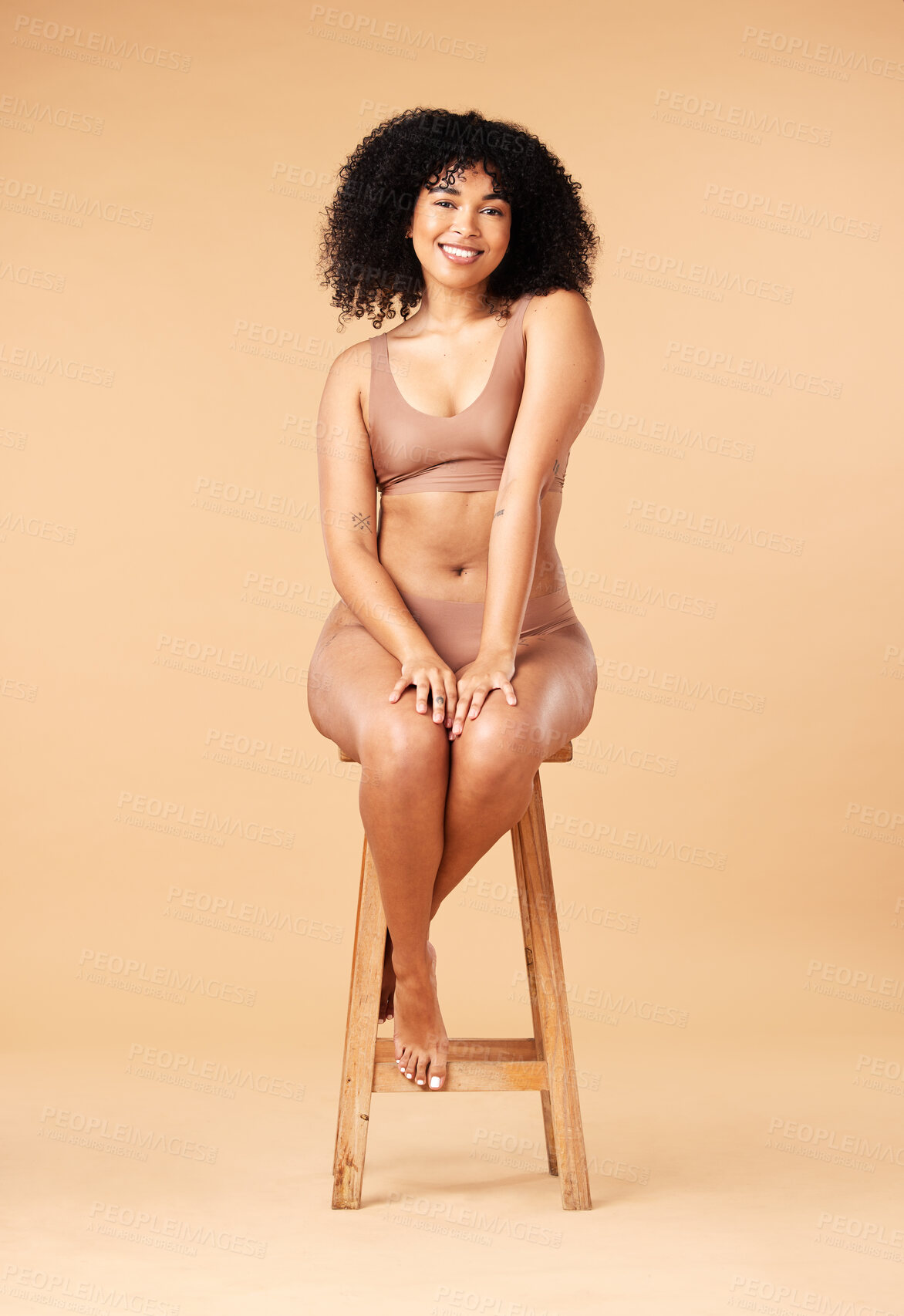Buy stock photo Body positive, beauty and black woman sitting on a chair for skincare and self care isolated in a studio brown background. Plus size, portrait and natural model smile, happy and glow due to cosmetic