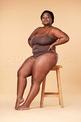 Buy stock photo Portrait, beauty and plus size with a model black woman posing on a chair in studio on a beige background. Wellness, underwear and natural with a female sitting on a stool for body positivity