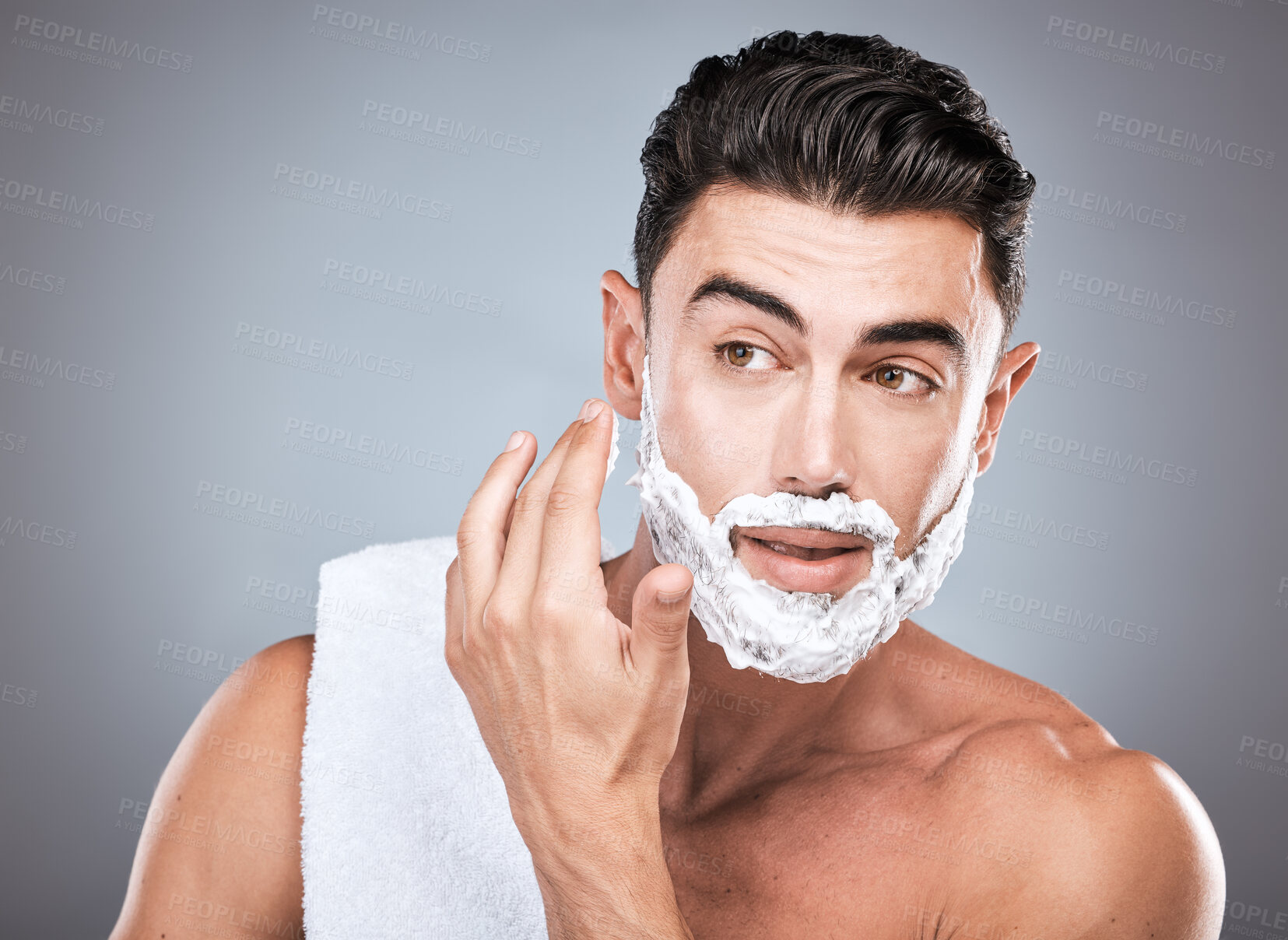 Buy stock photo Face, shaving foam and grooming with a man model in studio on a gray background for hair removal. Thinking, hand and skincare with a handsome young male in the bathroom for a shave in the morning