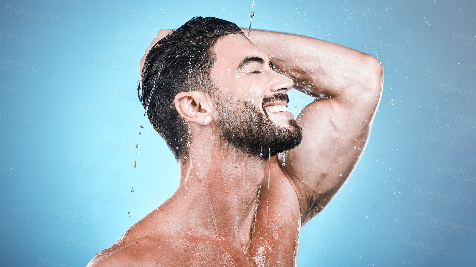 Buy stock photo Face skincare, water splash and man in shower in studio isolated on a blue background. Wellness, dermatology and happy male model cleaning, washing and bathing for healthy skin, self care and hygiene