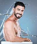 Water, splash and man in shower man, portrait for hygiene, 
beauty and skincare isolated on blue background. Smile, face and cleaning body with muscle, sustainability and happy with natural cosmetics