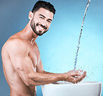 Water splash, portrait and man cleaning hands in studio isolated on a blue background for wellness, healthy skin or grooming. Hygiene dermatology, skincare and male model bathing or washing hand.