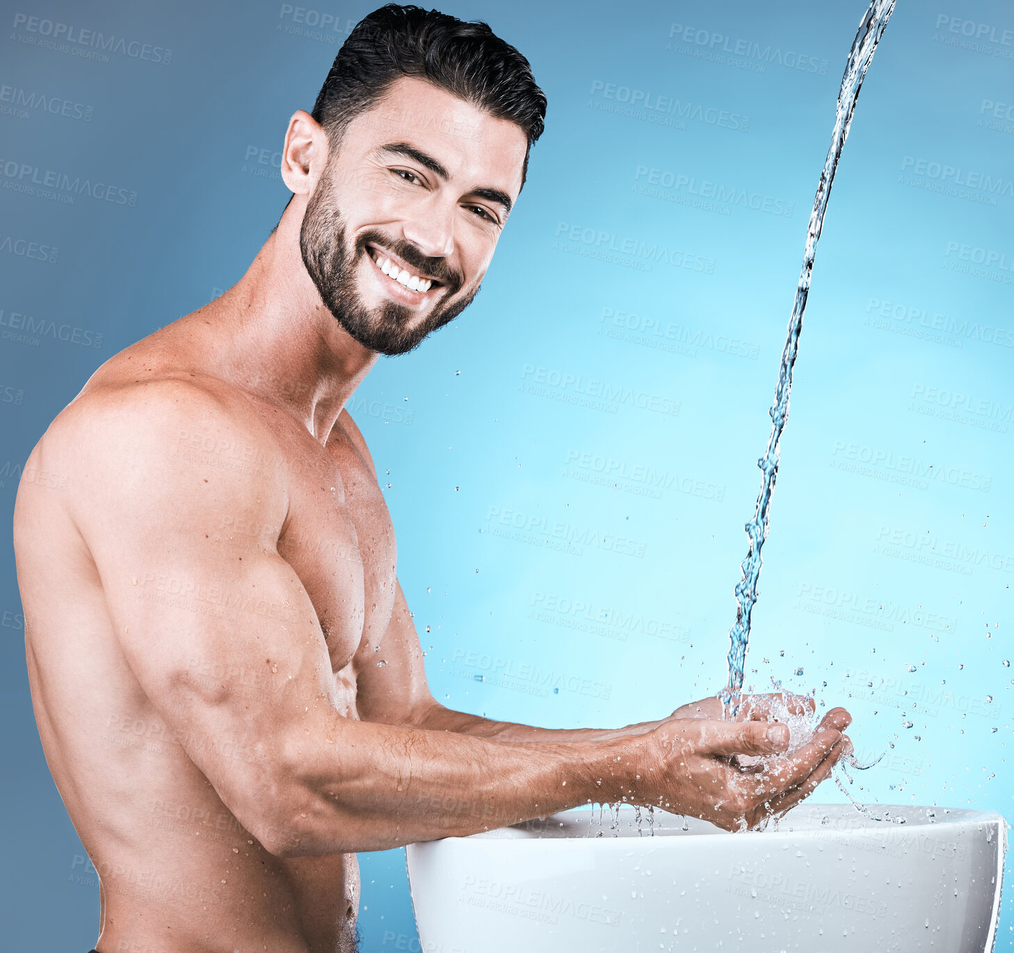 Buy stock photo Water splash, portrait and man cleaning hands in studio isolated on a blue background for wellness, healthy skin or grooming. Hygiene dermatology, skincare and male model bathing or washing hand.