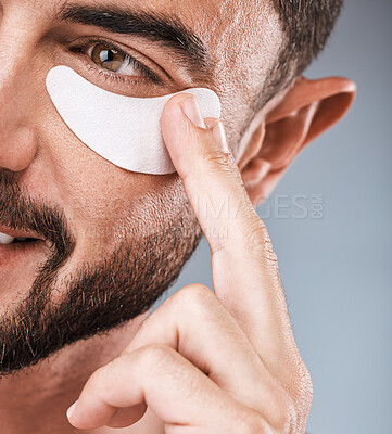 Buy stock photo Skincare, face and man with eye patch in studio isolated on a gray background for wellness. Thinking, dermatology and male model with cosmetics, facial treatment or mask product for healthy skin.