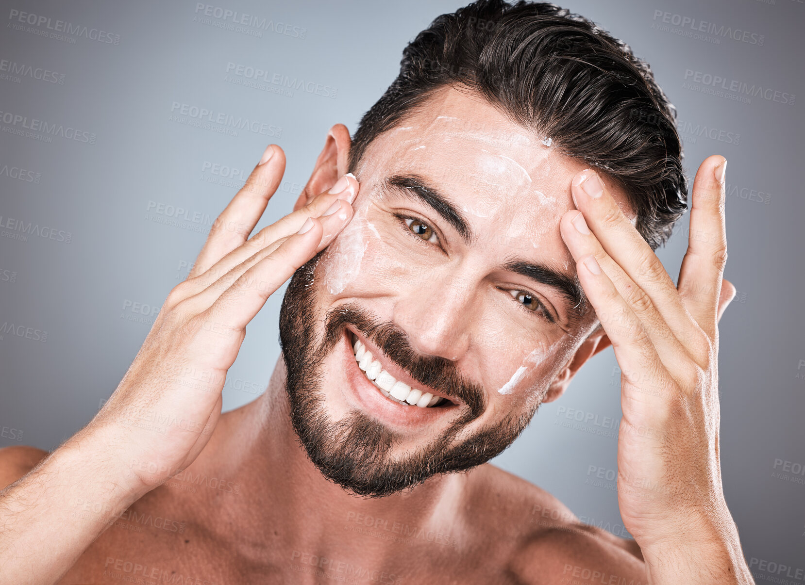Buy stock photo Skincare, face and man with cream in studio isolated on a gray background for facial wellness. Portrait, dermatology cosmetics and happy male model apply lotion, creme or moisturizer for healthy skin