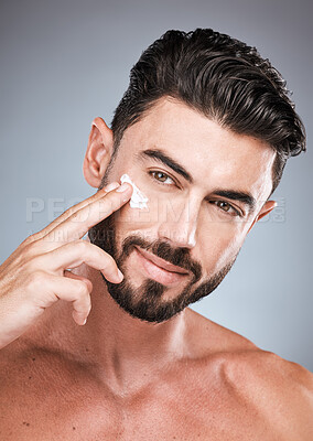 Buy stock photo Skincare, face cream and portrait of man in studio isolated on a gray background for wellness. Cosmetics, dermatology and young male model apply lotion, creme or moisturizer product for facial health