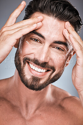 Buy stock photo Face, skincare and man with cream in studio isolated on a gray background for facial wellness. Portrait, forehead cosmetics and happy male model apply lotion, healthy creme or moisturizer product.