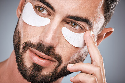 Buy stock photo Face, man and skincare eye patches in studio isolated on a gray background for wellness. Thinking, beauty dermatology and male model apply eyes mask, cosmetics or facial treatment for healthy skin.