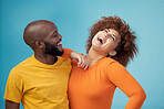 Love, laughing and interracial couple with a joke isolated on a blue background in a studio. Comic, funny and black man and woman smiling with happiness, care and confidence on a backdrop together