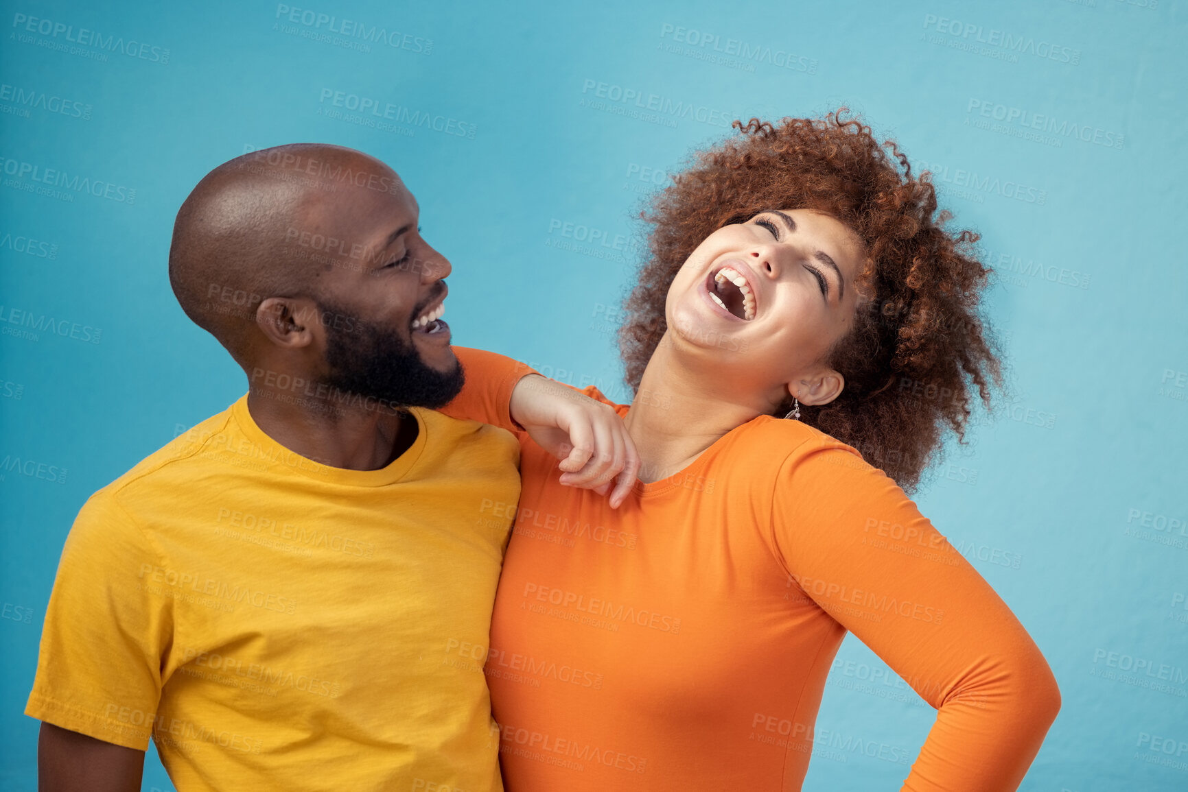 Buy stock photo Love, laughing and interracial couple with a joke isolated on a blue background in a studio. Comic, funny and black man and woman smiling with happiness, care and confidence on a backdrop together