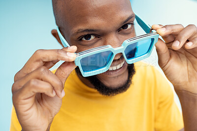 Buy stock photo Black man, sunglasses and comic face portrait on blue background with cool and trendy style or fashion. Happy young model person with glasses in studio for advertising designer brand, logo or color