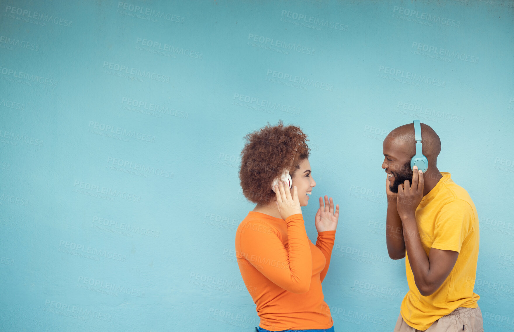 Buy stock photo Couple of friends listening to music isolated on a blue background with headphones for gen z mockup space. Black woman with happy partner or people with audio, podcast and youth technology mock up