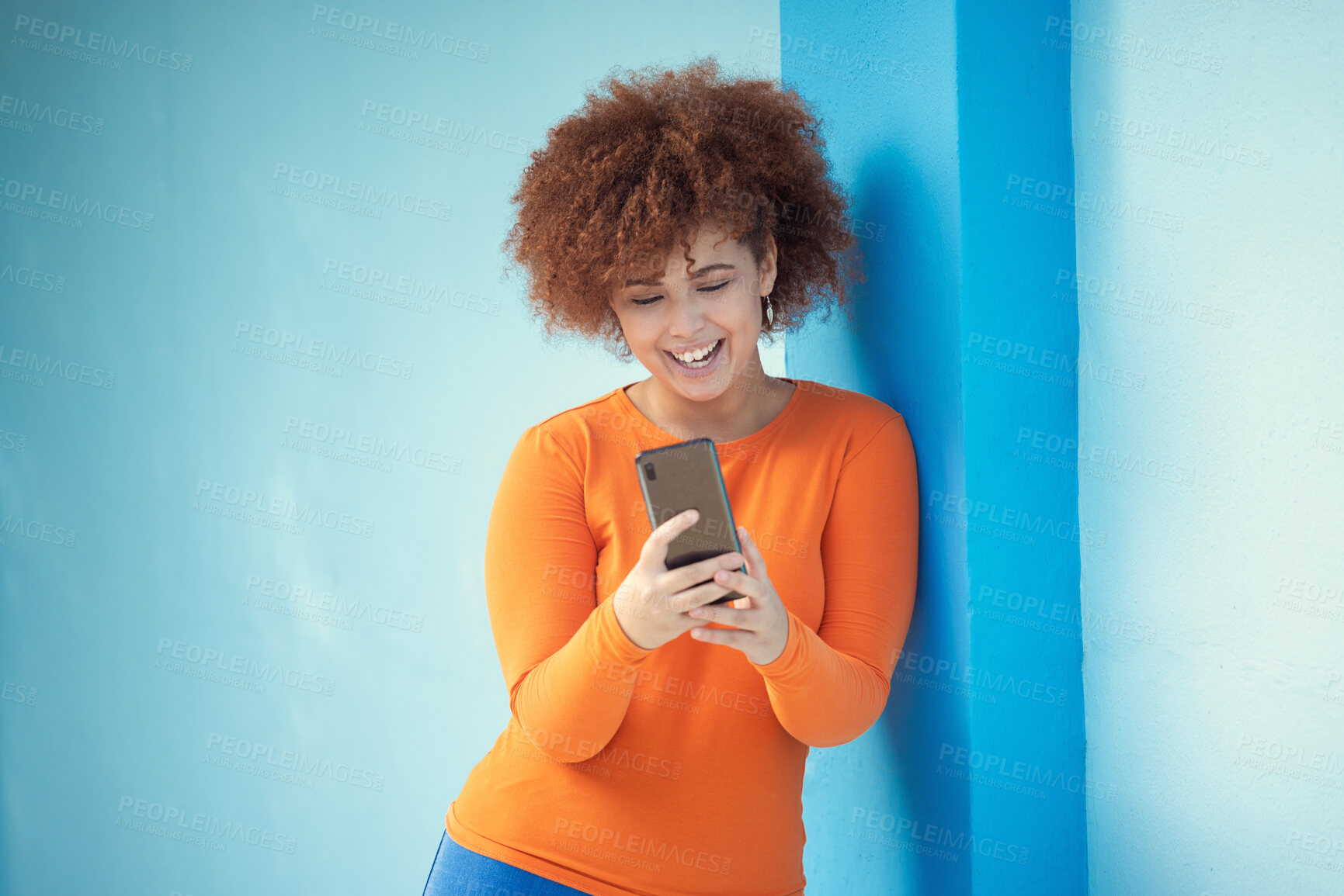 Buy stock photo Black woman, cellphone and laughing on mobile on blue wall of social media, technology or network. Happy young girl typing on smartphone of connection, reading funny notification and meme post online