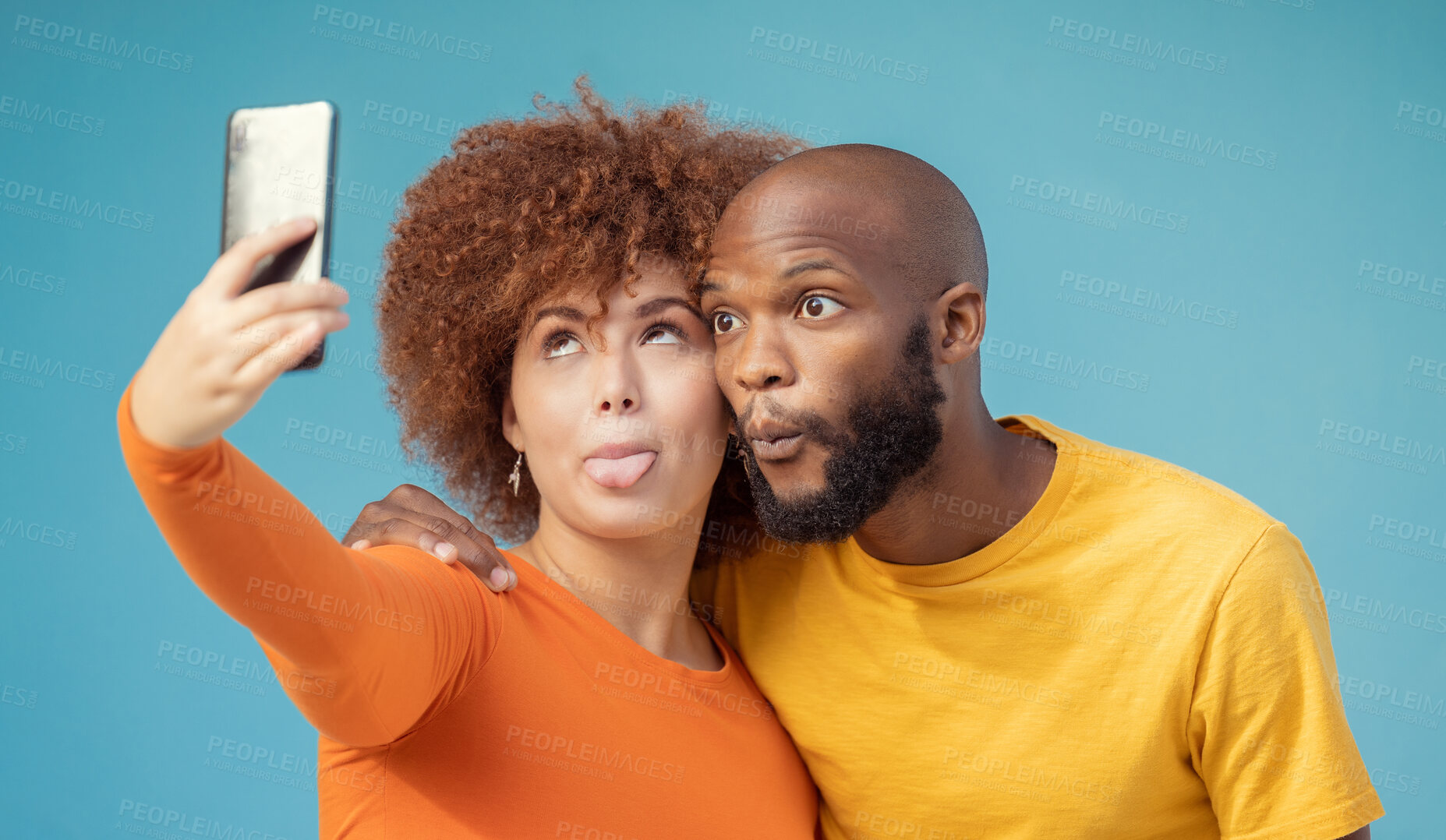 Buy stock photo Couple, hug and funny faces selfie on blue background, isolated mockup or wall mock up for social media. Comic, goofy and silly black man and woman on photography tech for interracial profile picture