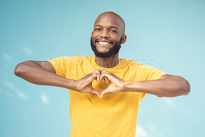 Buy stock photo Hand, heart and portrait of man in studio for love, happy and smile against a blue background space. Emoji, hands and face of male model relax with finger, frame and loving message, gesture and sign 