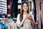 Phone, clothing store and happy woman typing a message or text online or a mobile app for shopping. Happiness, smile and female networking on social media with a cellphone in a retail fashion shop.