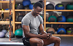 Phone, fitness and black man in gym training, workout or exercise social media or internet search for health tips. Bodybuilder, sports person listening to music or typing on smartphone chat or mobile