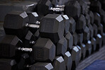 Fitness, workout and dumbbells in empty gym for exercise, bodybuilding development and sports training club. Background zoom of heavy steel weights, equipment and iron for lifting in wellness studio