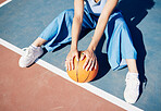 Basketball, hands and woman on the outdoor court floor with urban fashion for influencer beauty. Sport, model and young person sitting with gen z clothes with sports game equipment in summer 