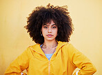 Portrait, fashion and attitude with an afro black woman in studio on a yellow background for style. Trendy, style and serious with an attractive young female posing alone on product placement space