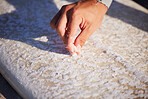 Hand, surfboard and wax with a sports man outdoor at the beach for surfing or recreation during summer. Fitness, surf and maintenance with a male surfer or athlete outside on the coast for surfing