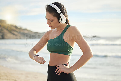 Buy stock photo Headphones, smartwatch and beach woman for workout, exercise or runner results, progress or wellness. Goals, check timer and mental health of sports person listening to music, podcast by sea or ocean