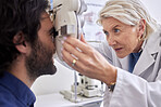 Doctor with a man in vision test or eye exam for eyesight by a senior optometrist or ophthalmologist. Senior optician helping check retina health of a patient or happy customer with medical insurance