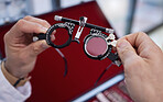 Optometry, healthcare and optometrist with trial lens for a eye test in a optical clinic. Vision, eyecare and hands with a prescription optic instrument or glasses for a exam in a ophthalmology store