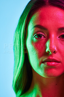 Buy stock photo Half portrait, skincare or glowing neon lighting on isolated blue background in self love or healthcare. Zoom, beauty model or woman face in creative fantasy green, pink or lights aesthetic in makeup