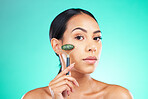 Portrait, jade roller and woman with face massage in studio for wellness, grooming or skincare on blue background. Face, facial and massaging tool by girl model relax, skin or product while isolated