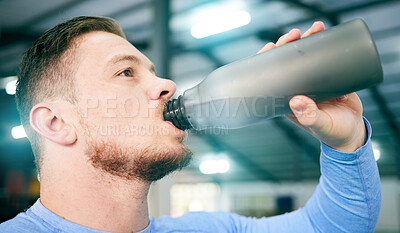 Buy stock photo Gym, fitness and man drinking water during training, exercise and intense cardio, serious and thirsty on blurred background. Hydration, athletic and male with bottle during workout at sports center