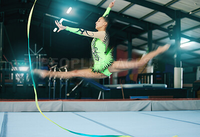 Gymnastics, woman and jump with ribbon and motion blur, sport in gym with action and speed for fitness. Athlete, moving with rhythmic gymnast, flexibility and pose with sports and splits in air