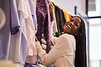 Clothes, retail and happy black woman shopping in a boutique, laugh and smile while feeling fabric. Fun, fashion and girl customer excited for clothing sale, discount or outfit choice in store