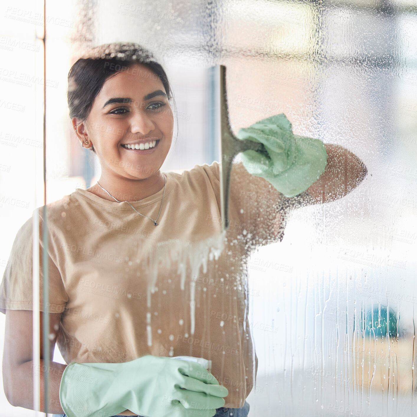 Buy stock photo Happy, smile and girl cleaning window with spray bottle and soap or detergent, housekeeper in home or hotel. Housework, smudge and woman or professional cleaner service washing off glass in apartment