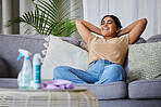 Woman, relax and sofa after cleaning house with smile, satisfaction and pride in home living room. Cleaner, rest and happy on lounge couch with spray, cloth and hygiene product on table in apartment