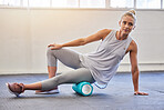 Fitness, physiotherapy and massage, woman with foam roller on floor for leg tension and support in yoga workout at gym. Health, pilates and massaging for sports physio, girl on ground rolling muscle.