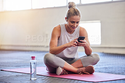 Buy stock photo Exercise, relax and woman with phone on floor reading email or text after yoga workout at gym. Health, pilates and technology, girl on ground with smartphone checking fitness app online siting on mat
