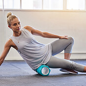 Fitness, physio and pilates, woman with roller on floor for leg tension ...