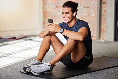 Buy stock photo Bodybuilder, gym floor and texting with smile on chat app, social media or meme on internet for happiness. Man, fitness and exercise for health, wellness or relax at training for online communication