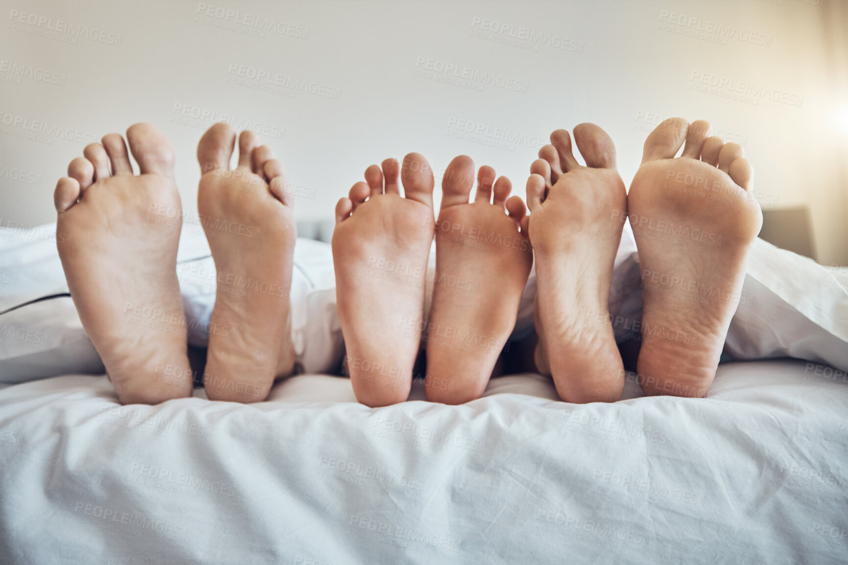 Buy stock photo Family feet, bed and together with kid, parents and sleeping on holiday for bonding, care and happiness. Bedroom, people and sleep with mom, dad and child on vacation to relax, break and hospitality