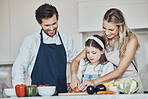 Learning, parents or girl cooking vegetables as a happy family in a house kitchen with organic food for dinner. Development, father or mother teaching, helping or cutting tomato with a healthy child