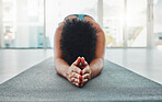 Yoga, arm stretching and prayer hands of a black woman in a gym for zen, relax and exercise. Pilates, peace and meditation training of an athlete in prayer pose on the floor feeling calm from stretch