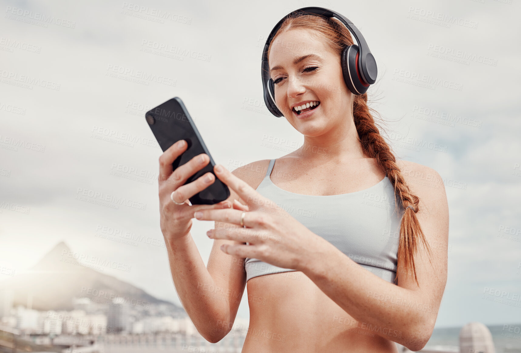 Buy stock photo Headphones, phone and woman doing workout in the city while listening to music, podcast or radio. Fitness, wellness and female athlete networking on social media with cellphone after outdoor exercise